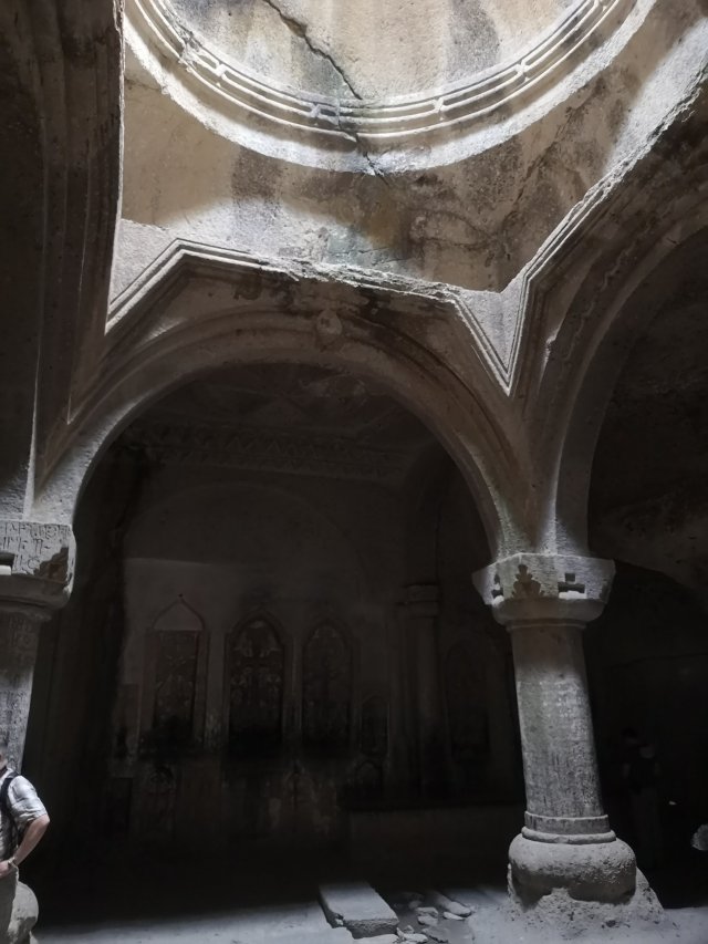 Jerevan Kyrka med pelare. Mörkt rum med ljus som kommer in från taket